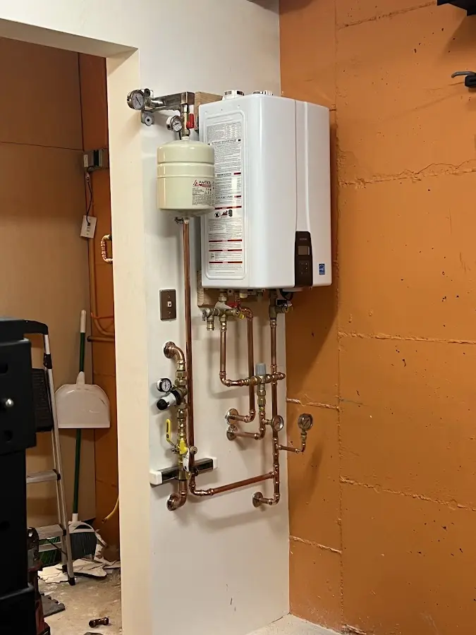 Plumbing technician inspecting water heater connections in Wrightstown